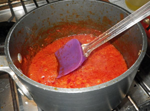 The homemade sauce is reduced in the pot to a thick, spreadable consistency.