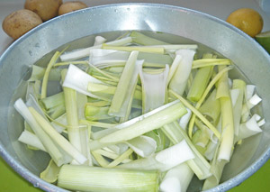 Clean leeks by separating the leaves and swishing them in a water bath. Scoop the leeks out leaving the dirt behind.